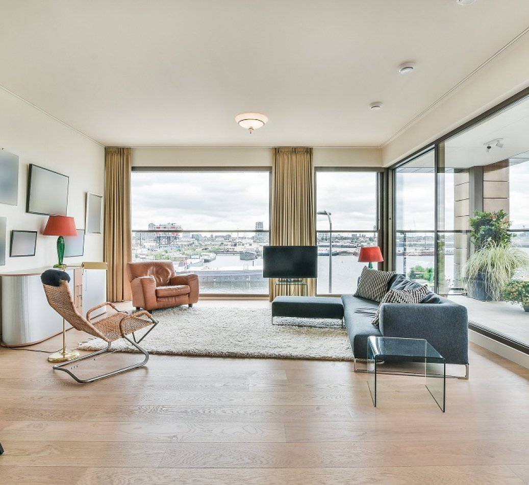 Modern interior design of contemporary open space apartment with comfortable sofa and soft carpet in lounge zone with large windows